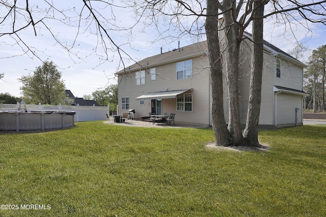back of property featuring a lawn, a patio, and an outdoor pool