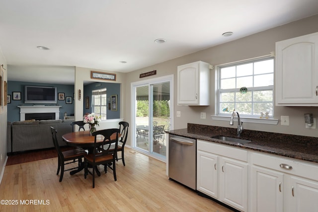 kitchen with dark stone counters, dishwasher, white cabinetry, and a sink