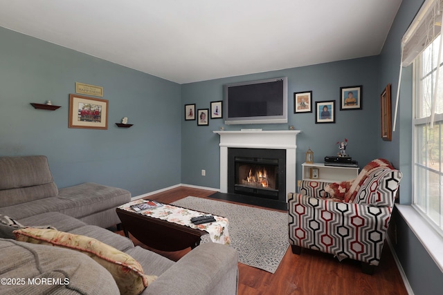 living area with dark wood-style floors, baseboards, and a fireplace with flush hearth