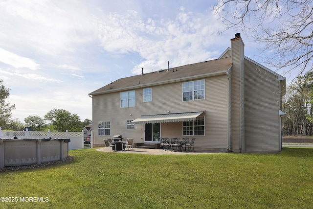 back of property with a yard, a chimney, an outdoor pool, and a patio