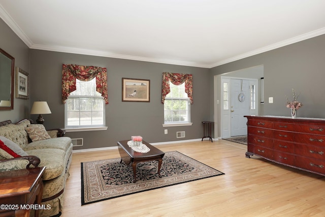 living room with ornamental molding, plenty of natural light, and light wood-style floors
