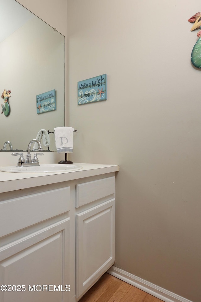 bathroom featuring baseboards, wood finished floors, and vanity