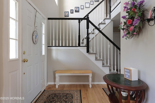 foyer entrance featuring baseboards, stairs, a wealth of natural light, and wood finished floors