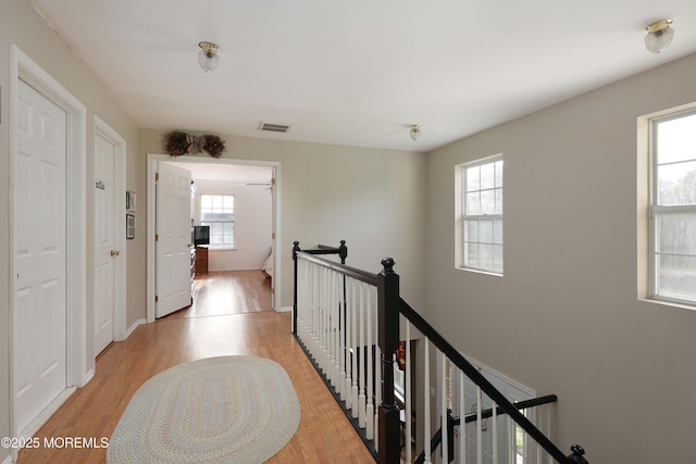 hallway with a healthy amount of sunlight, an upstairs landing, and light wood-type flooring