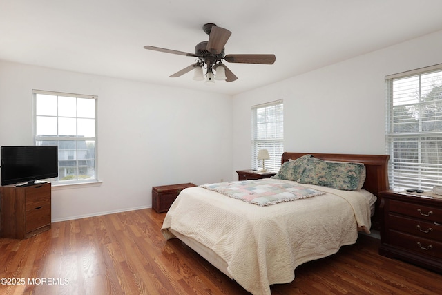 bedroom featuring baseboards, multiple windows, ceiling fan, and wood finished floors