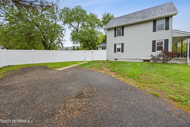 rear view of property with roof with shingles, a lawn, and a fenced backyard