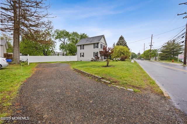 view of front of home with a front lawn, roof with shingles, and fence