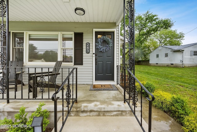 view of exterior entry featuring a yard and a porch