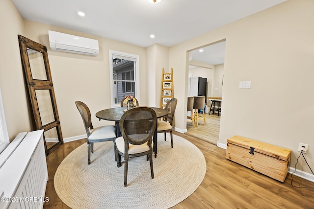 dining space with radiator, recessed lighting, a wall unit AC, baseboards, and light wood-style floors