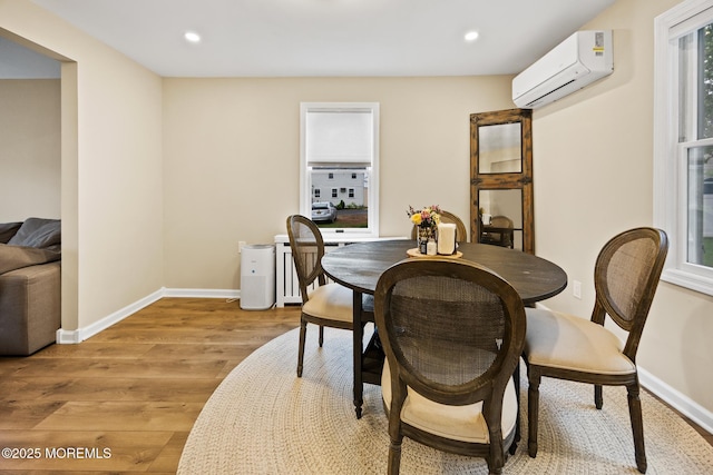 dining area featuring baseboards, light wood-style floors, a wall mounted air conditioner, and recessed lighting