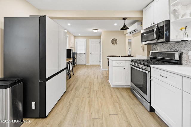 kitchen featuring stainless steel appliances, light wood-type flooring, white cabinetry, decorative backsplash, and a wall unit AC