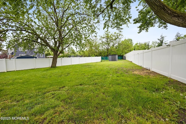 view of yard with a fenced backyard, an outdoor structure, and a shed