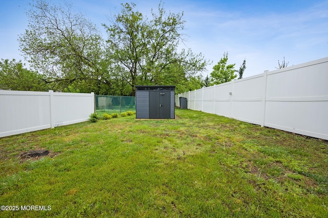 view of yard featuring an outbuilding, a fenced backyard, and a storage unit