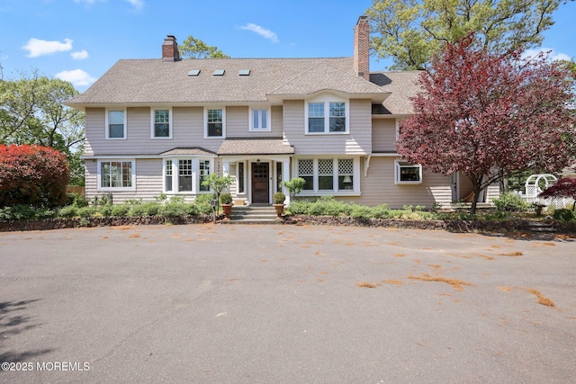 view of front of house featuring a chimney and a shingled roof