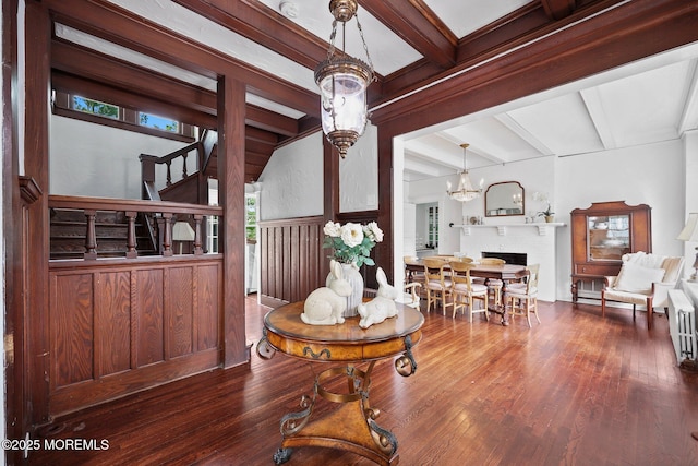 dining room featuring an inviting chandelier, stairs, hardwood / wood-style flooring, beamed ceiling, and a fireplace