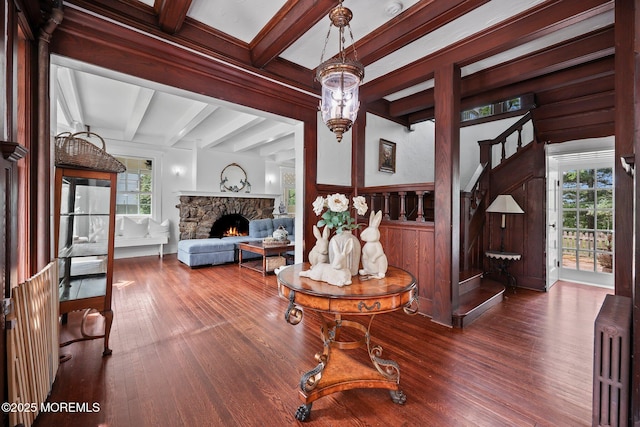 living room with beamed ceiling, radiator heating unit, plenty of natural light, and wood finished floors