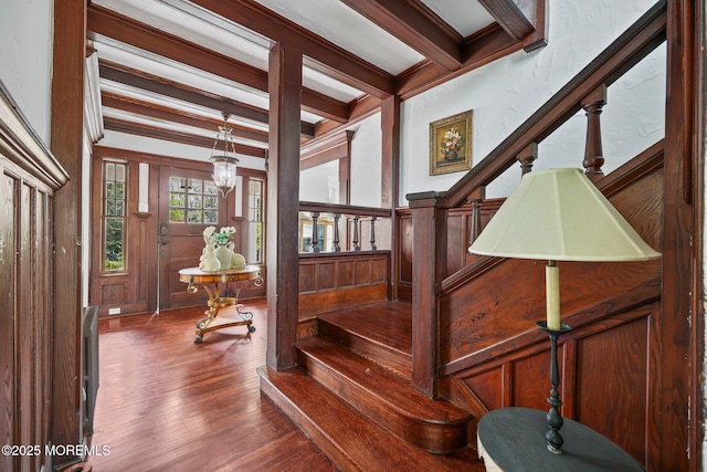 stairs featuring beamed ceiling, a decorative wall, and wood finished floors