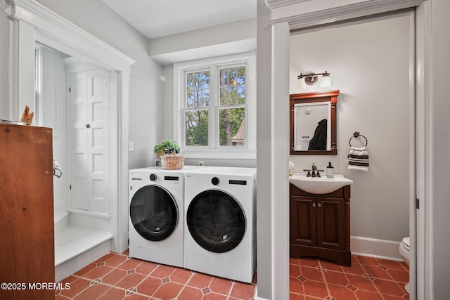 clothes washing area with washer and dryer, laundry area, baseboards, and a sink