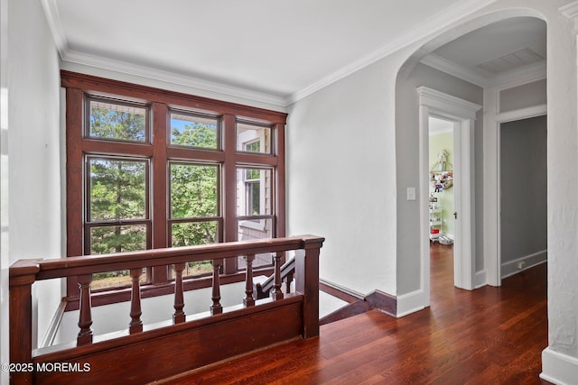 hallway with arched walkways, baseboards, crown molding, and wood finished floors