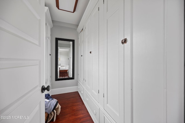 hall featuring dark wood-style flooring and baseboards