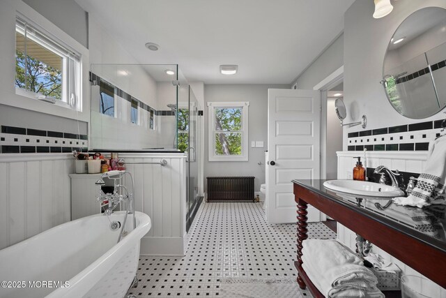 bathroom featuring a stall shower, radiator heating unit, a sink, tile patterned floors, and a soaking tub