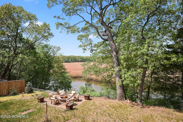 view of yard featuring a fire pit, a water view, and fence