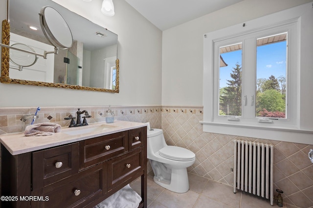 bathroom with radiator, a wainscoted wall, tile walls, tile patterned flooring, and vanity