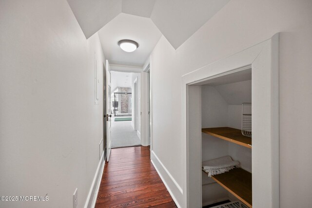 corridor with baseboards, dark wood finished floors, and vaulted ceiling