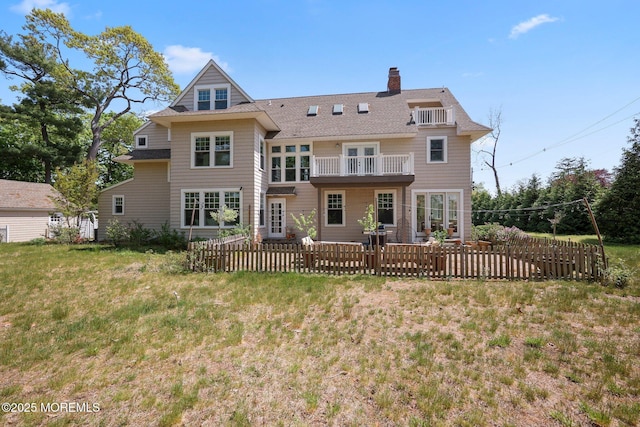 back of property with a balcony, a chimney, fence, a patio area, and roof with shingles