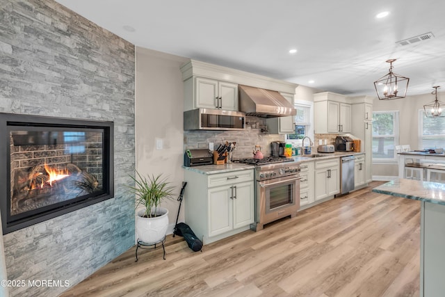 578 Petunia Ln N, Whiting, NJ 08759 - kitchen featuring appliances with stainless steel finishes, range hood, a sink, light wood-style floors, and tasteful backsplash