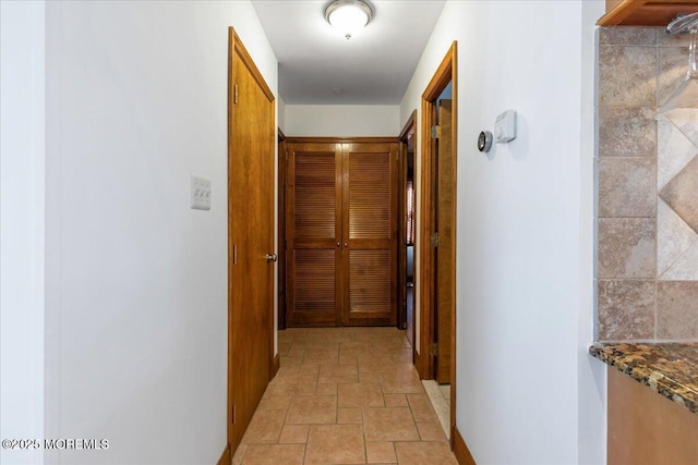 hall with stone tile flooring and baseboards