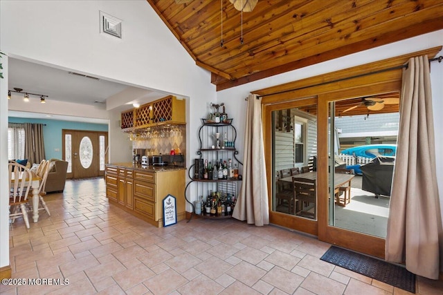 kitchen with a ceiling fan, stone tile flooring, and vaulted ceiling
