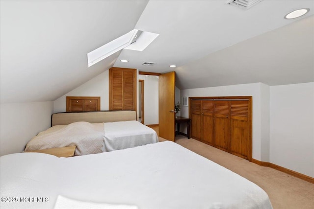 bedroom featuring lofted ceiling, light colored carpet, a skylight, and baseboards
