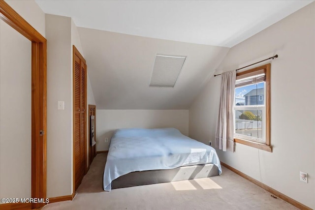 bedroom with lofted ceiling, carpet floors, baseboards, and a closet