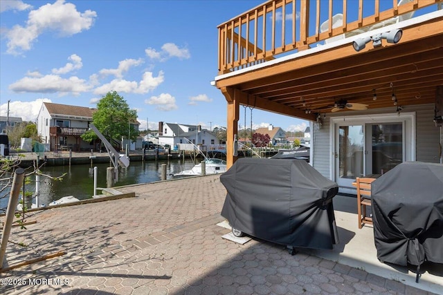 view of patio featuring a water view, a boat dock, grilling area, a ceiling fan, and a residential view