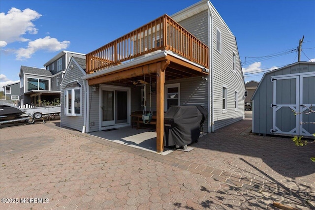 back of property with a shed, an outdoor structure, a patio, and a deck