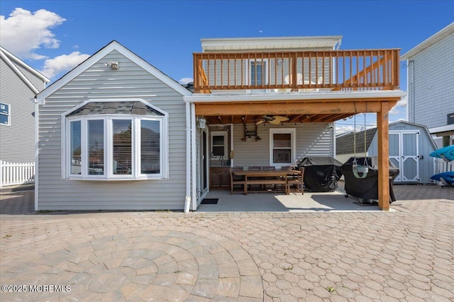 back of property featuring a shed, a patio, an outdoor structure, a wooden deck, and fence