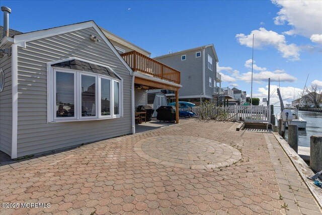 view of patio / terrace with a storage shed, an outbuilding, fence, and a deck with water view