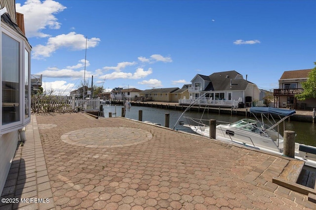 view of patio with a residential view, a dock, and a water view