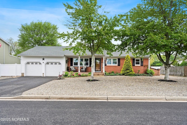 2207 Riviera Pkwy, Point Pleasant, NJ 08742 - ranch-style house featuring asphalt driveway, an attached garage, fence, covered porch, and brick siding