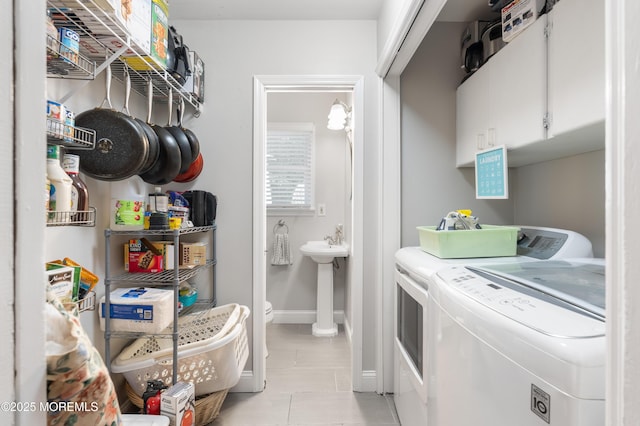 laundry area with washing machine and clothes dryer, light tile patterned floors, baseboards, and a sink