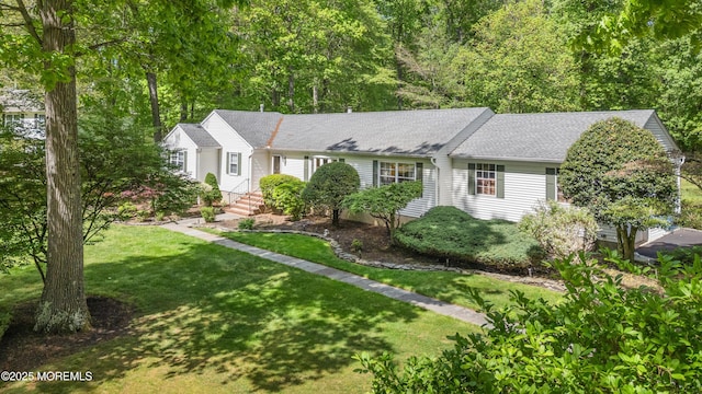 ranch-style home featuring roof with shingles and a front yard