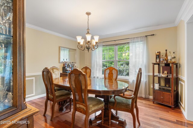 dining room with a chandelier, crown molding, and light wood-type flooring