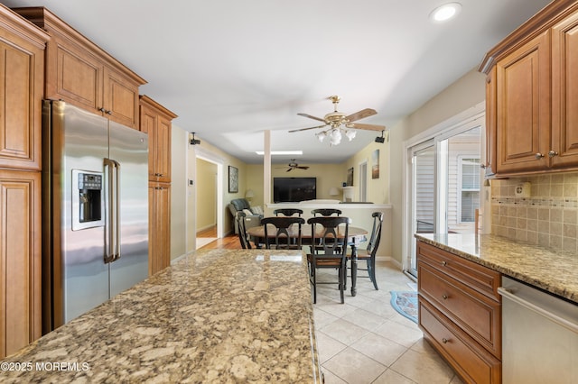 kitchen featuring appliances with stainless steel finishes, a ceiling fan, decorative backsplash, light stone countertops, and recessed lighting