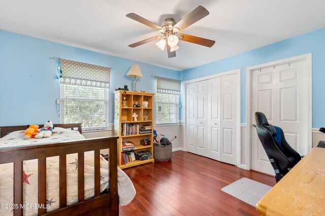 bedroom featuring an office area, wood finished floors, a ceiling fan, and a closet