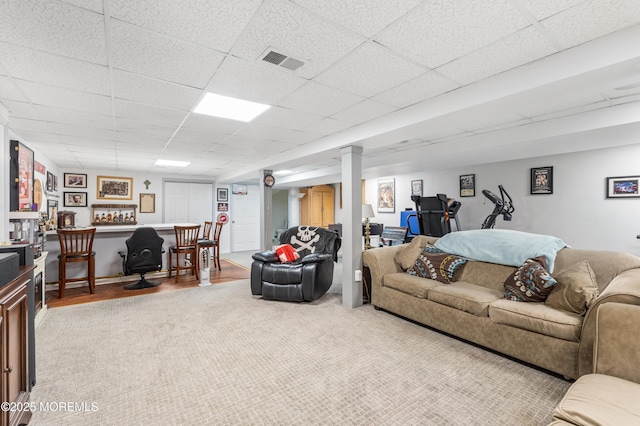 living area with a drop ceiling and carpet