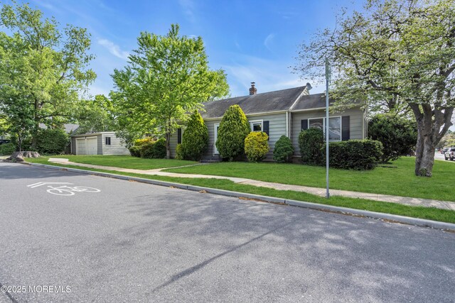 view of front of home featuring a front lawn, a garage, a chimney, and roof with shingles