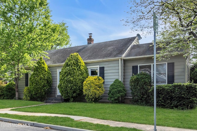 single story home featuring a front yard, a chimney, entry steps, and roof with shingles