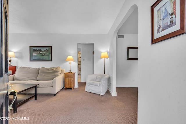 carpeted living room with arched walkways and baseboards