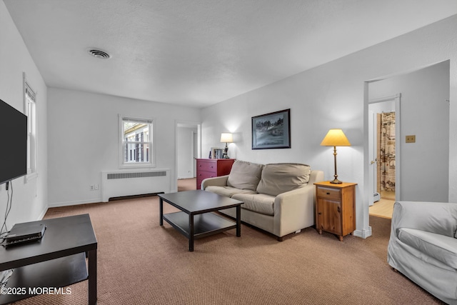 living area featuring radiator heating unit, light carpet, baseboard heating, and baseboards